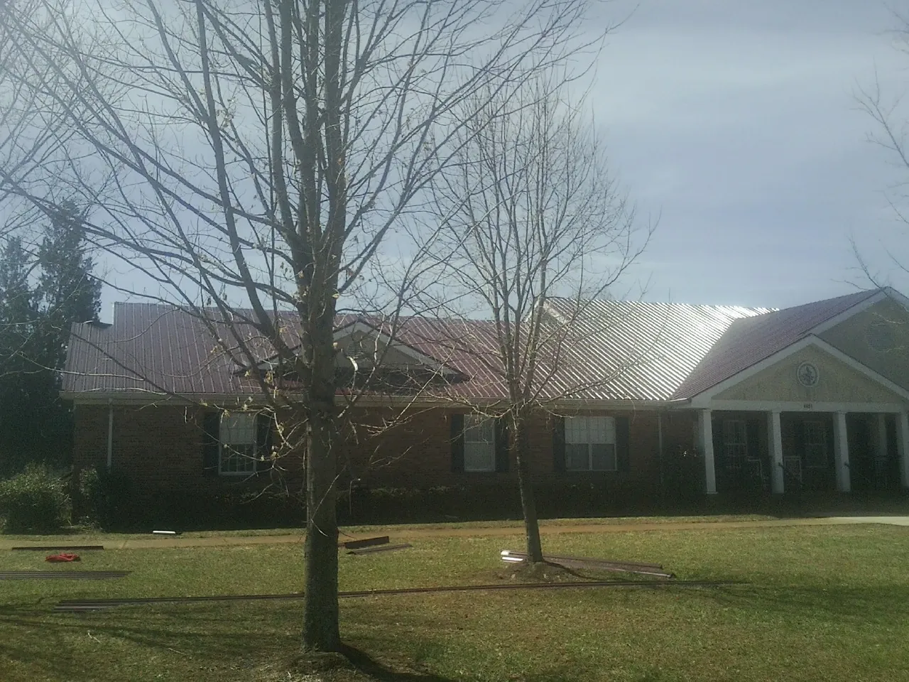 Red metal roof on a brick building seen from the front lawn in Germantown
