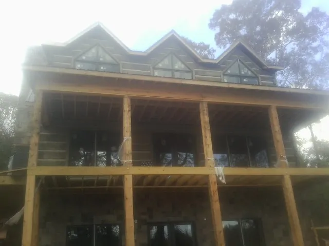 Dormers and porch framing on a large log home under construction — Roof Coating work by our crew in Germantown